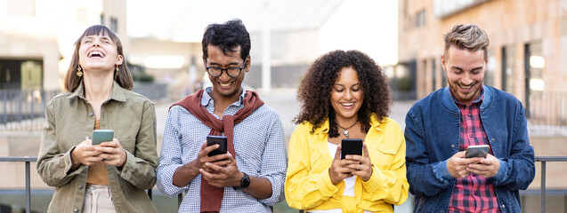 Fototapeta Horizontal banner or header with multiracial friends laughing using smartphone in the university district of the city - Young people addicted by mobile smart phones obraz