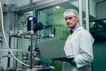 Fototapeta na wymiar Scientist holding laptop and controlling rotational vaporizer during CBD oil extraction, hemp oil extraction process.