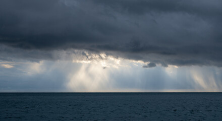 Storm clouds with Sun beam through heavy sky.