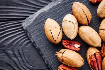 delicious fresh pecans on a black rustic wooden background