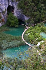 Vertical shot of a curved boardwalk path along waterfalls on world-famous Plitvice Lakes, Croatia - obrazy, fototapety, plakaty