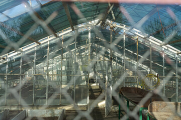 Rabitz. Old abandoned greenhouse behind a chain-link fence