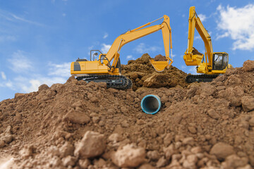 Obraz premium Excavator is digging in the construction site pipeline work ,on a blue sky background