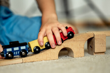 a boy at home in a room is building a railway, a child is playing with a toy train. Educational toys for home and kindergarten. Wooden Environmental Toys