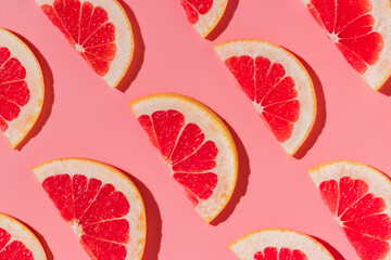Grapefruit slices minimal background on pink, harsh shadows, flat lay
