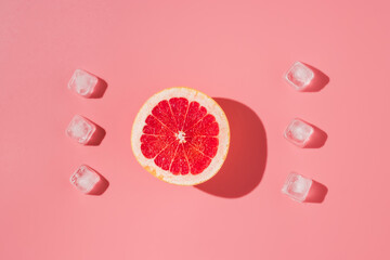 Grapefruit with ice cubes on pink background. Summer minimal concept, top view, flat lay