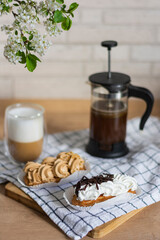 Sweet french two eclairs and double day cup coffee pot morning cappuccino and coffee pot with coffee on wooden table 