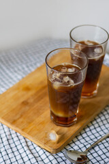 Homemade two glasses in highball glass goblets cold iced coffee drink with orange juice and syrup. Concept: summertime cold drinks copy space 
