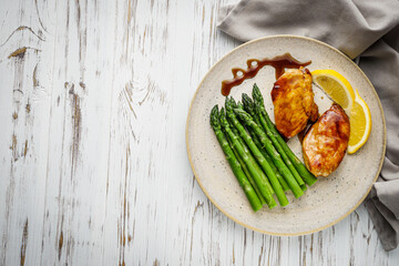 boiled green asparagus and grilled chicken on a white wooden rustic background