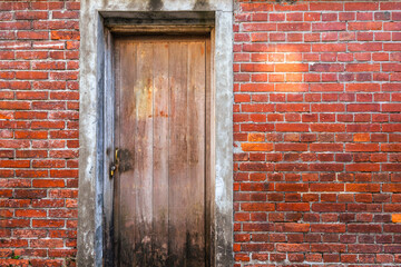 A old locking wooden door with the red brick wall.