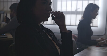 Silhouette of business woman talking on headset and typing on laptop computer. Female staff working