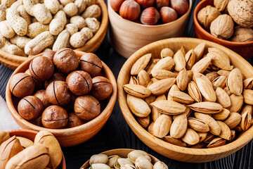 set of different nuts on a black rustic wooden background
