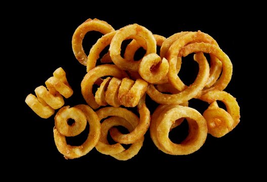 Top view of appetizing crispy golden French fries with curled shape on black isolated background