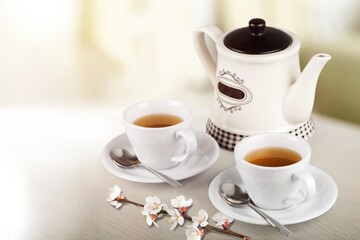 Tea concept with white tea set of cups and teapot with fresh tea on the desk