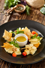 Cheese platter on wooden background in rustic style. Appetizer for wine - georgian cheese with honey. Cheese platter on black plate on wooden table.