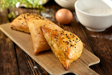 aditional uzbek pastry - samsa with meat. Uzbek pies with meat and puff dough on wooden background in rustic style. Meat samosa with ingredients. East pastry.