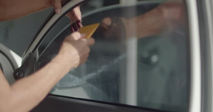 Installs tint film for car glass with and spatula purge the air under the film that is pasted on the glass.