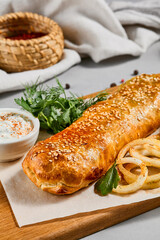 Meat pie with greens and onion on wood plate. Eastern food - beef pie with sesame. Eastern pastry with Minced meat.