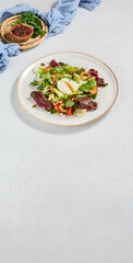 Green salad with sliced roast beef and pachot egg. Roast beef salad with vegetables and egg on concrete background in minimal style. Aesthetic composition with meat salad, textile and spices.