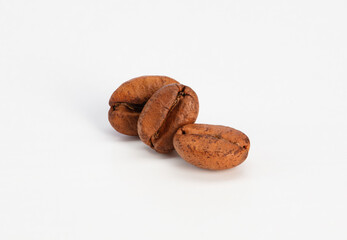 Three roasted coffee beans on a white background. Selective focus	
