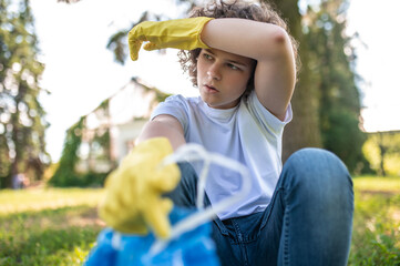 Cute young volunteer looking tired after gathering garbage