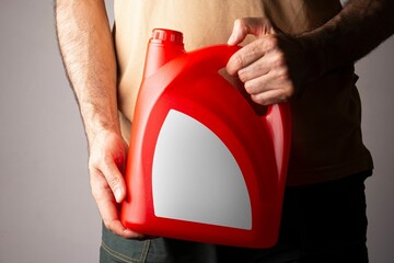 Man holding a red kitchen detergent bottle with closed cap at his hand, editable mockup series