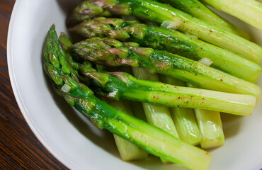 Fried asparagus in a white plate, close up.