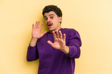 Young caucasian man isolated on yellow background being shocked due to an imminent danger