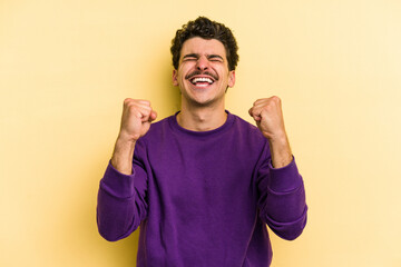 Young caucasian man isolated on yellow background celebrating a victory, passion and enthusiasm, happy expression.