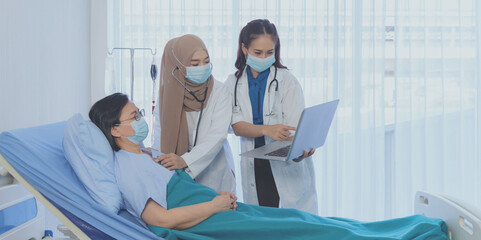 Muslim female doctor using stethoscope checking pressure and young asian female doctor hold laptop...