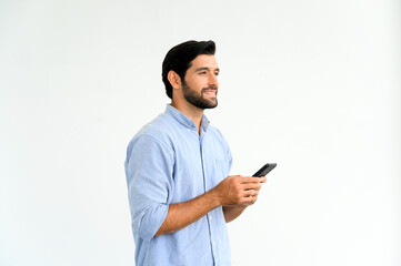 Portrait of smiling macho bearded guy in blue t-shirt using smartphone standing over white background.