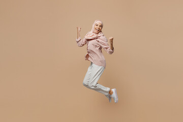 Fototapeta na wymiar Young happy arabian asian muslim woman she wear abaya hijab pink clothes jump high do winner gesture isolated on plain pastel light beige background. People uae middle eastern islam religious concept.