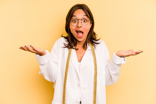 Young nutritionist hispanic woman isolated on yellow background receiving a pleasant surprise, excited and raising hands.