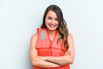 Young caucasian woman wearing life jacket isolated on blue background laughing and having fun.