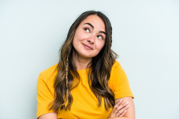 Young caucasian woman isolated on blue background dreaming of achieving goals and purposes