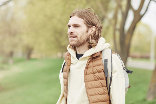 Young man with backpack behind his back spending time on fresh air during his walking