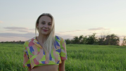 4K. Happy young woman posing at sunset in a field.