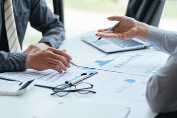 Group of business people meeting, discussing, analyzing graphs, financial data, and planning a marketing project together