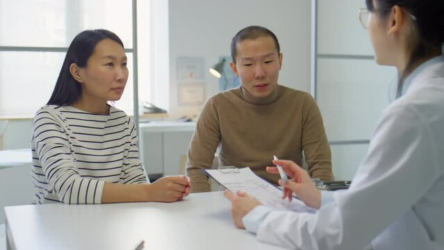 Asian family couple speaking with female doctor while having consultation in fertility clinic