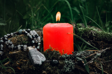 burning candle, a symbol of the moon, an amulet lying on the moss on a dark natural background....