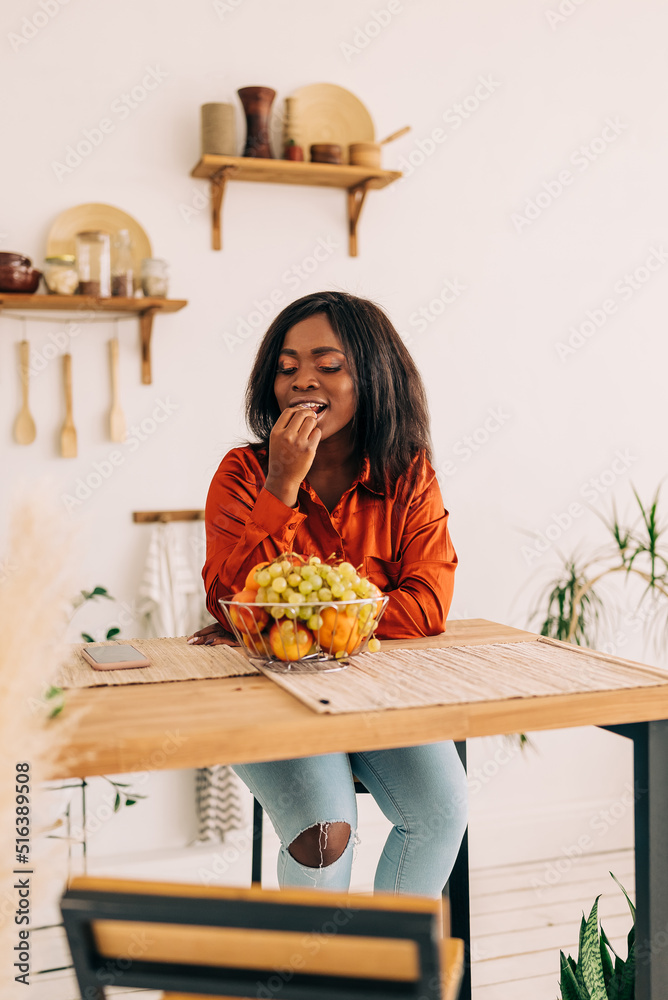 Wall mural Beautiful young woman eating yogurt in the kitchen in the morning. Healthy food. Close up. Portrait shot