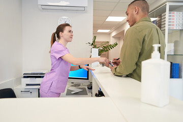 Female receptionist talking with client in modern clinic
