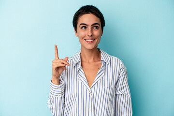 Young caucasian woman isolated on blue background indicates with both fore fingers up showing a...