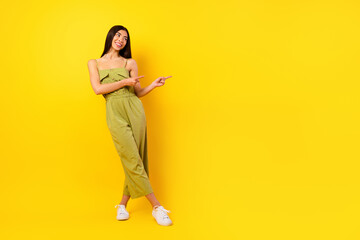 Full length photo of adorable nice vietnamese girl look direct fingers empty space ad isolated on yellow color background