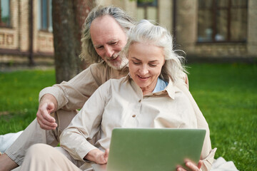 Two happy mature people looking at modern laptop