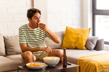 Young mixed race man eating popcorn sitting on the sofa