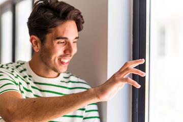 Young caucasian man looking through window closeup face