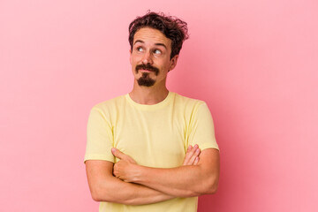 Young caucasian man isolated on pink background dreaming of achieving goals and purposes