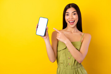 Naklejka premium Photo of charming astonished person direct finger empty space phone display isolated on yellow color background
