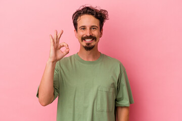 Young caucasian man isolated on pink background cheerful and confident showing ok gesture.
